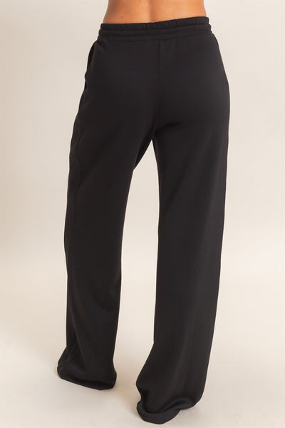 back view of model wearing  black pants with a light background