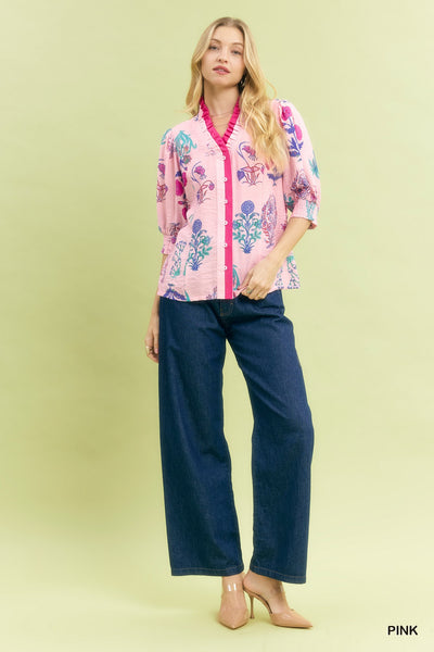 Woman wearing a pink floral blouse and blue jeans on a light green background