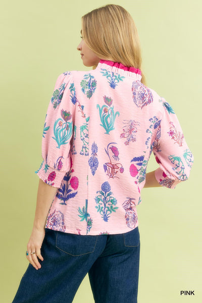 Woman wearing a pink floral blouse with blue jeans on a light green background