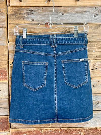 Blue denim skirt on a clear hanger against a wooden background