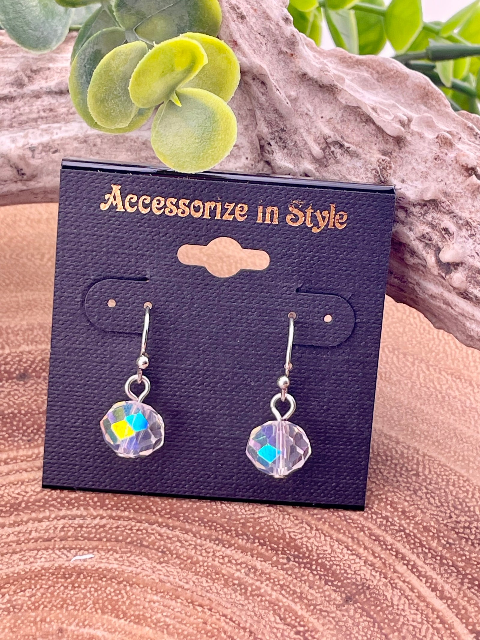 Crystal earrings on a 'Accessorize in Style' card with green foliage in the background
