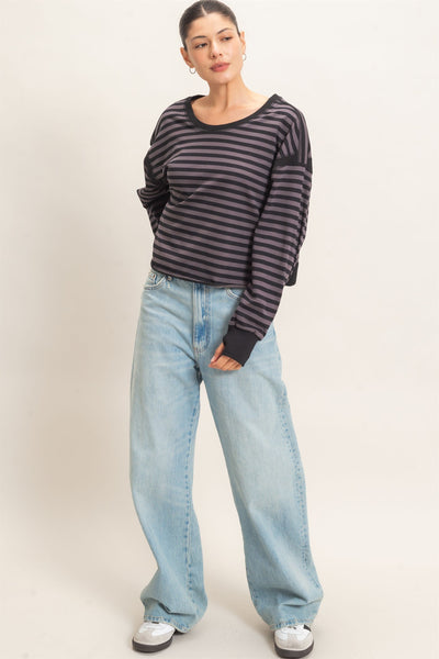 model wearing a black striped sweater and jeans with a light background