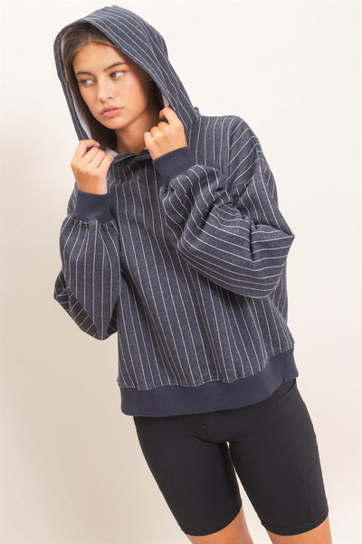model wearing a navy striped hoodie with black shorts in front of a light background
