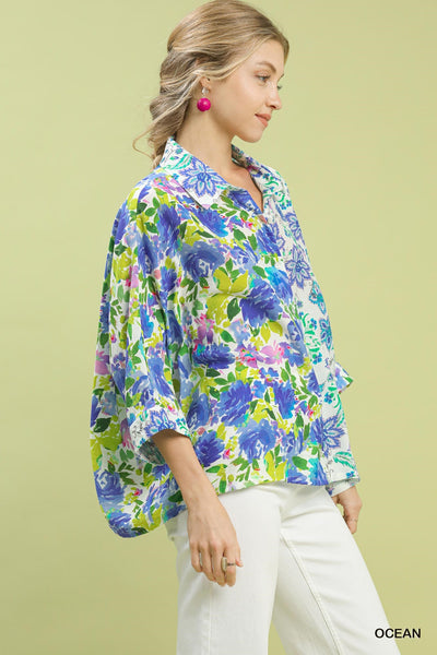 Woman wearing a colorful floral blouse against a light green background