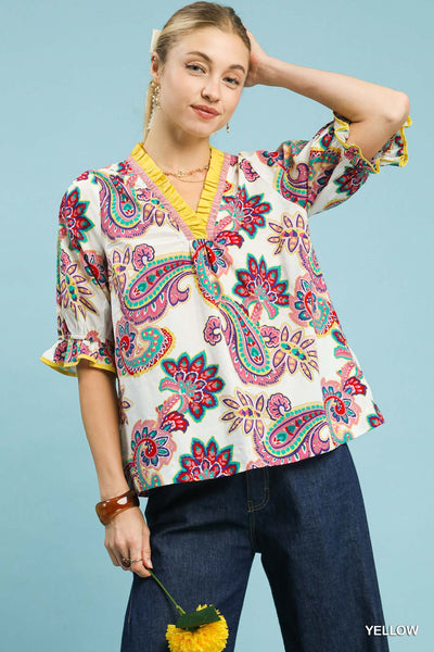 Woman wearing a colorful paisley blouse with a plain background