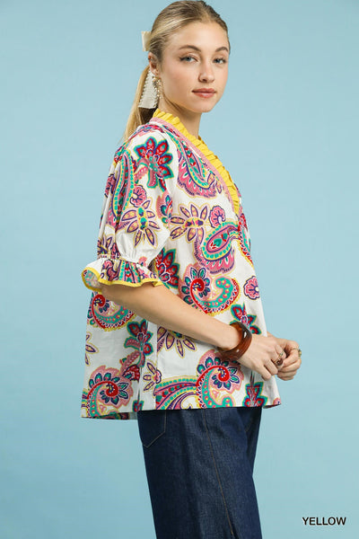 Woman wearing a colorful paisley patterned top against a blue background