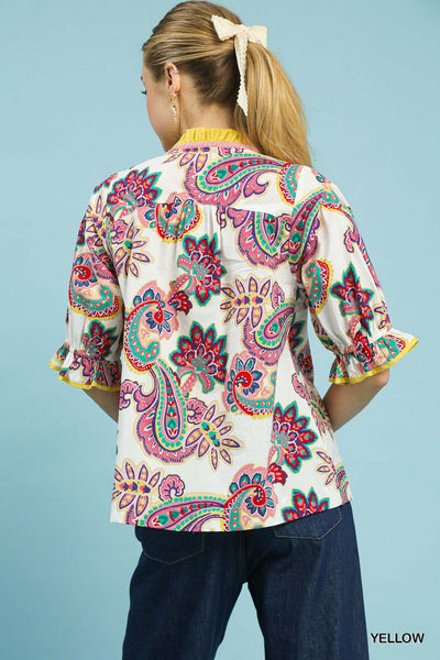 Woman wearing a colorful paisley patterned blouse against a blue background