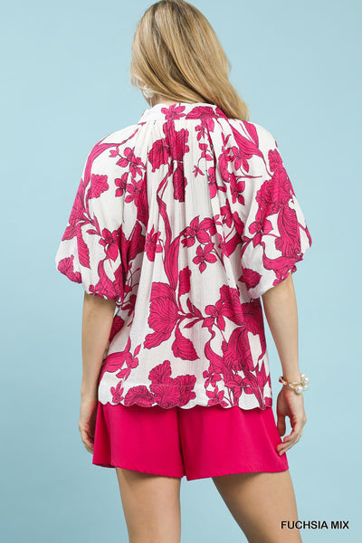 Woman wearing a pink floral top and shorts against a light blue background