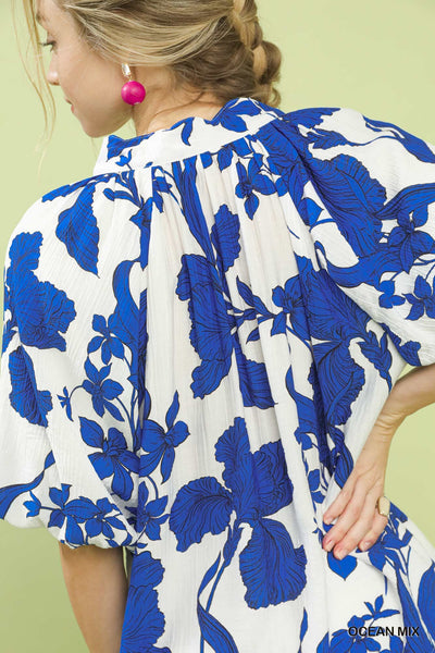 Woman wearing a blue and white floral dress against a light green background