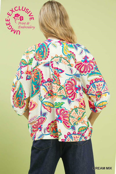 Person wearing a colorful floral shirt with a green background
