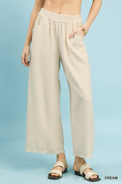 Beige wide-leg pants worn by a person on a light blue background