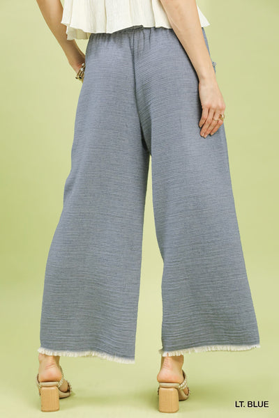 Light blue wide-leg pants worn by a person on a light green background