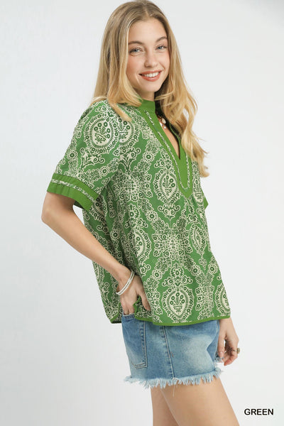 Woman wearing a green floral print top and denim shorts on a white background