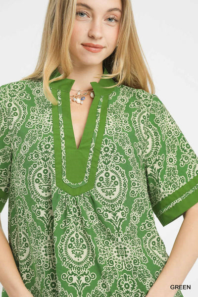 Woman wearing a green patterned top with a white background