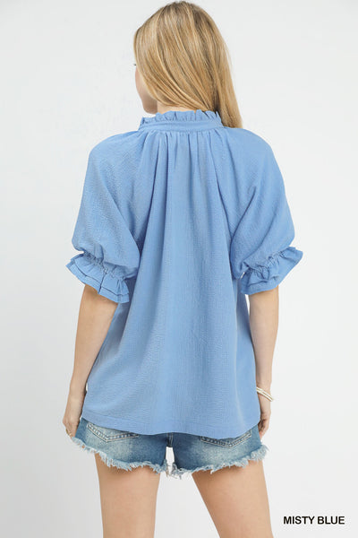 model wearing a blue v neck blouse with denim shorts