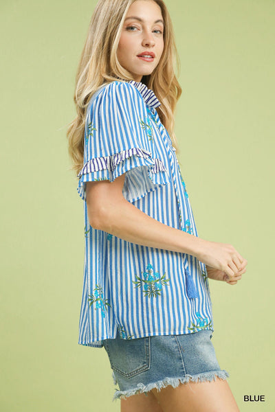 Woman wearing a blue and white striped shirt with a floral design on a light green background