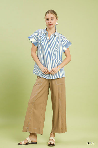 Woman wearing a striped shirt and beige pants on a light green background