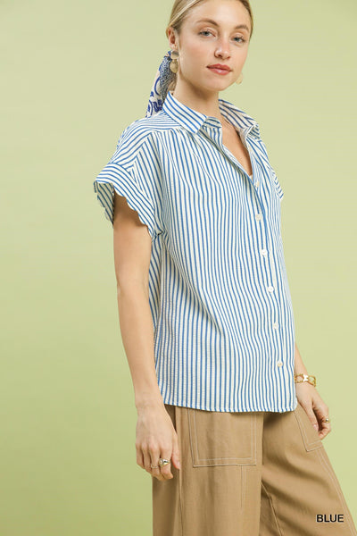 Woman wearing a blue and white striped shirt with a plain background