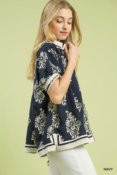 Woman wearing a navy patterned top against a light green background