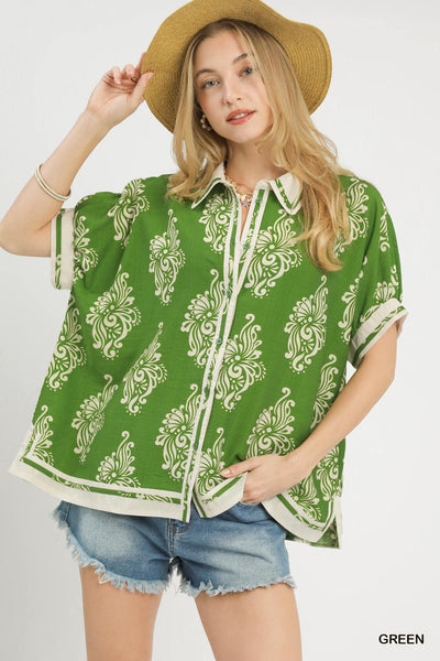 Woman wearing a green patterned shirt and denim shorts on a white background