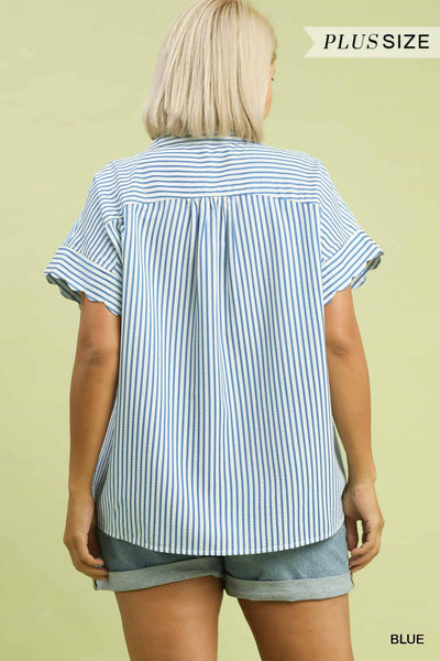 Woman wearing a blue and white striped shirt and shorts on a light green background