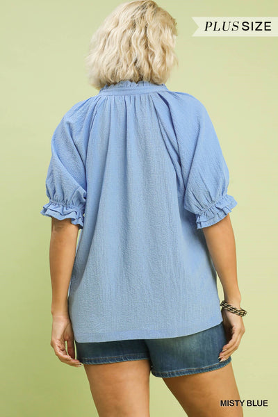 plus model wearing a blue v neck blouse with denim shorts
