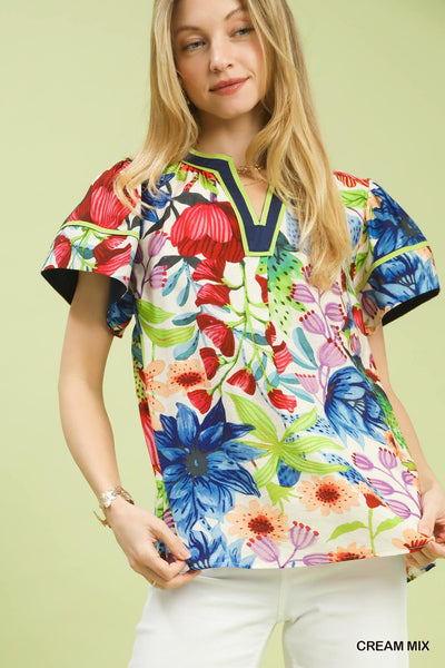 model wearing cream multicolor floral blouse & white pants
