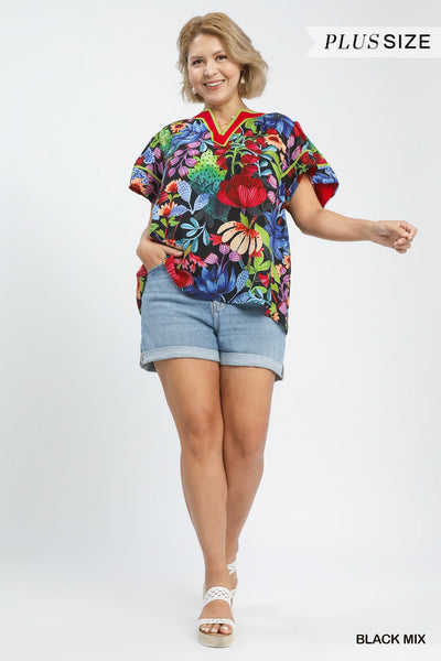 plus model wearing black multicolor floral blouse with cuffed denim shorts