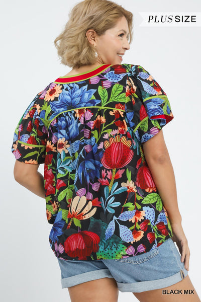 plus model wearing black multicolor floral blouse with cuffed denim shorts