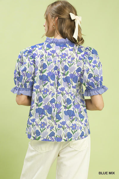 model wearing a blue floral top & white pants
