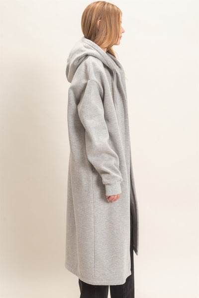 side view of model wearing a black outfit with oversized long gray coat