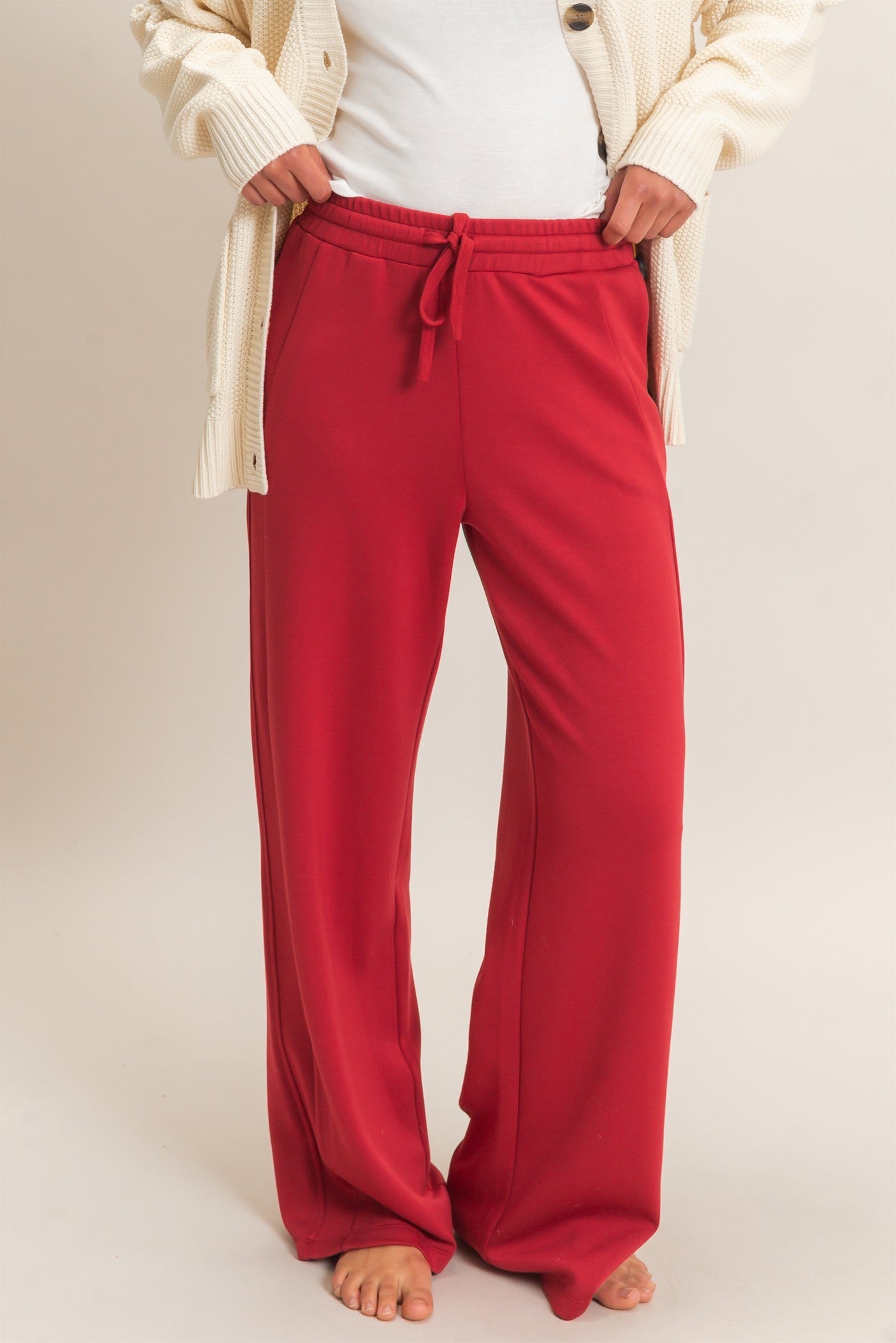 model wearing a white shirt & red pants with a light background