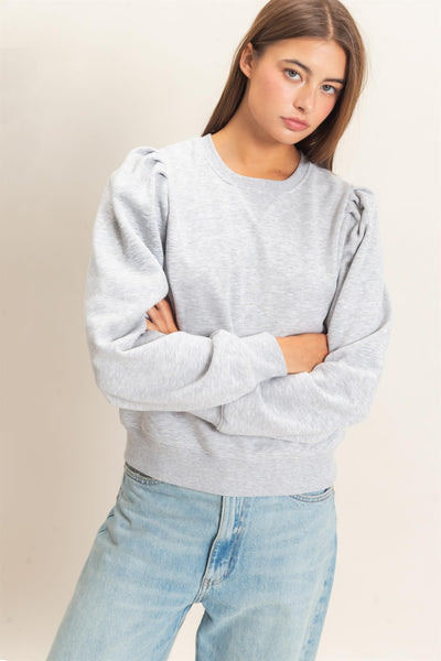 model wearing heather gray top and jeans in front of a light background