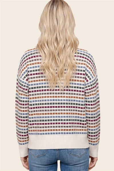 back of woman wearing a cream and multi color striped sweater and jeans