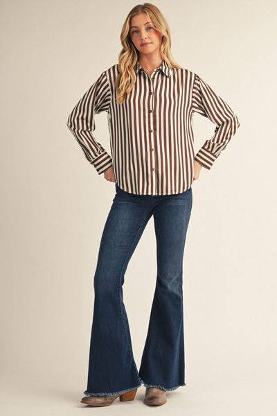 model wearing a brown striped top with jeans before a beige background