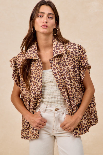 Woman wearing a leopard print vest over a white top and pants on a beige background