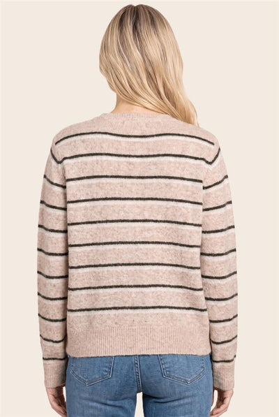 A woman viewed from the back wearing a beige knit sweater with thin black horizontal stripes and blue jeans, against a plain light beige background.