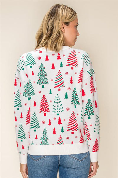 A woman shown from the back wearing a white long-sleeve crewneck sweater with an all-over Christmas tree pattern in red and green, paired with blue jeans against a plain beige background.