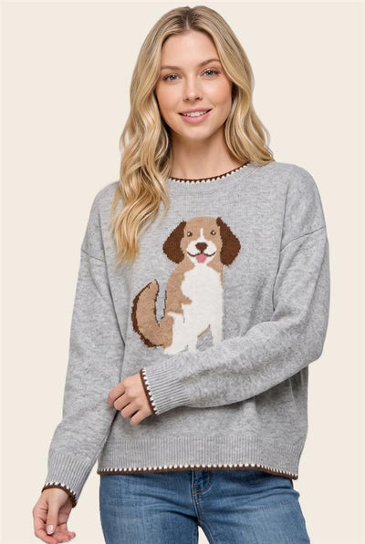 A woman wearing a heather gray knit sweater with a brown and white beagle dog graphic on the front, paired with blue jeans, against a solid beige background.