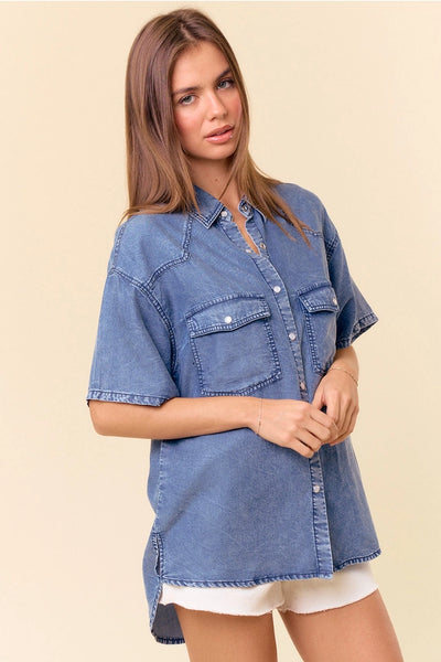 model wearing a short sleeve denim top & white shorts with a tan background