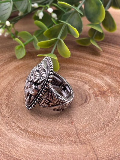 silver floral ring with stamped band on a wooden surface