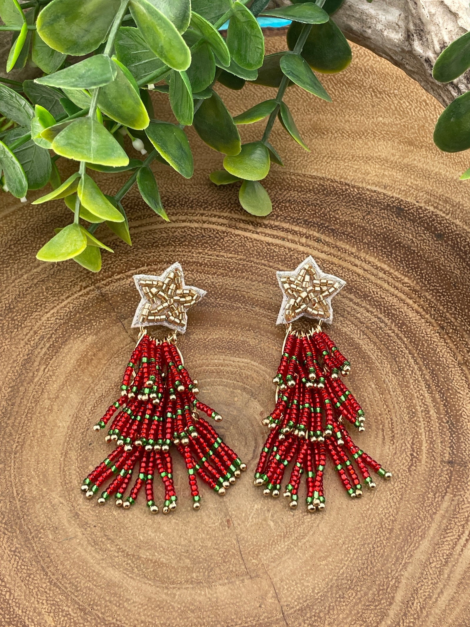 gold star red bead christmas tree earrings on wooden surface