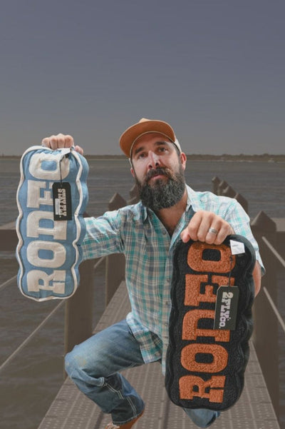 Man holding two Rodeo pillow on a dock with a helicopter in the background