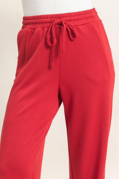 model wearing a white shirt & red pants with a light background