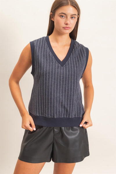 model wearing a striped v neck sleeveless top with black shorts on a light background
