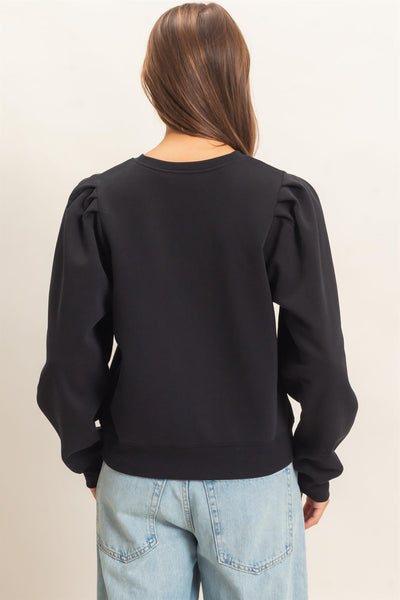 back of model wearing black top and jeans in front of a light background