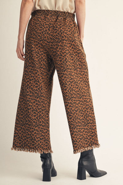 back of model wearing elastic waist leopard pants with raw hem and black boots on a light background