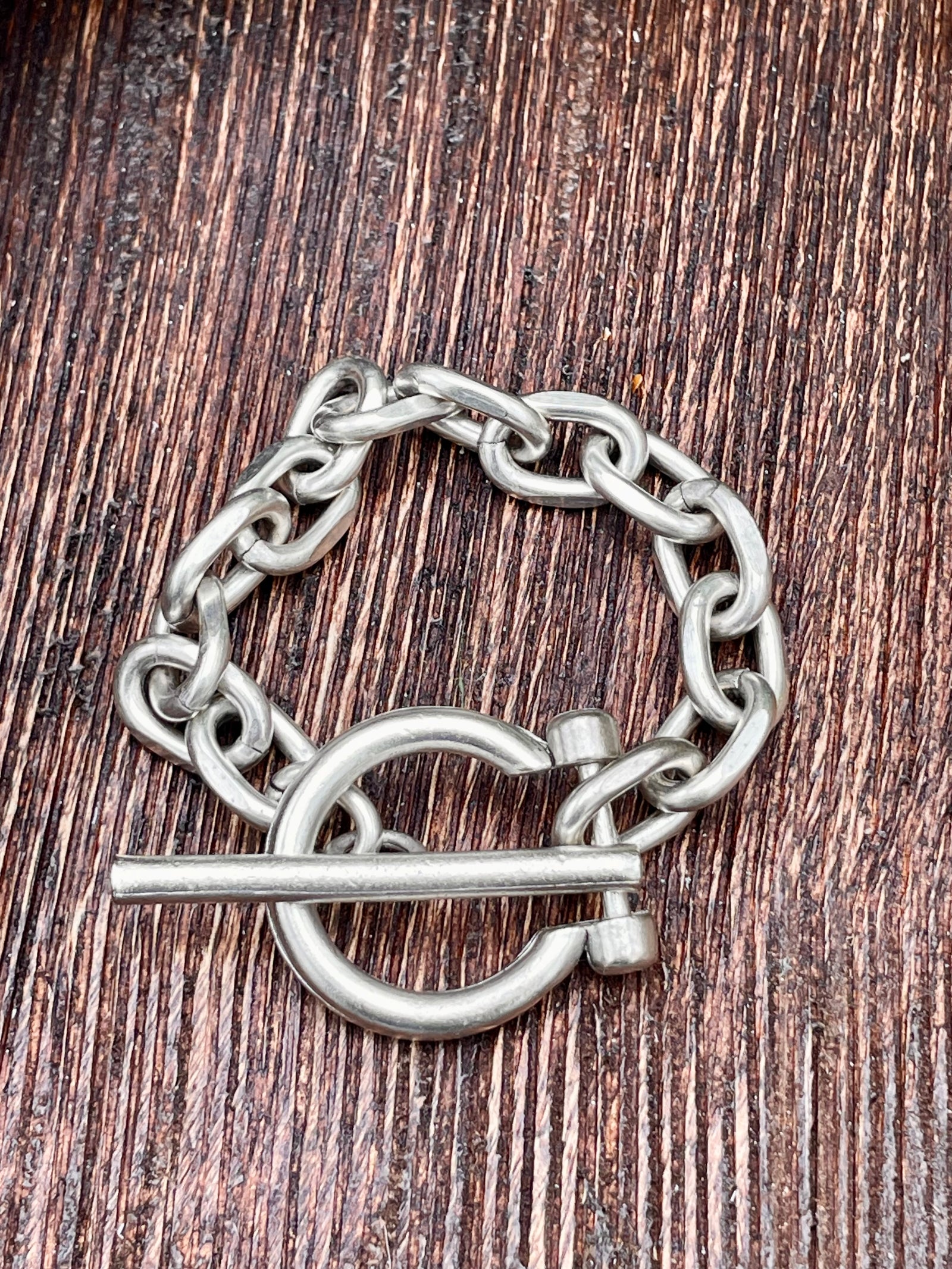 Silver chain bracelet with toggle on a wooden surface