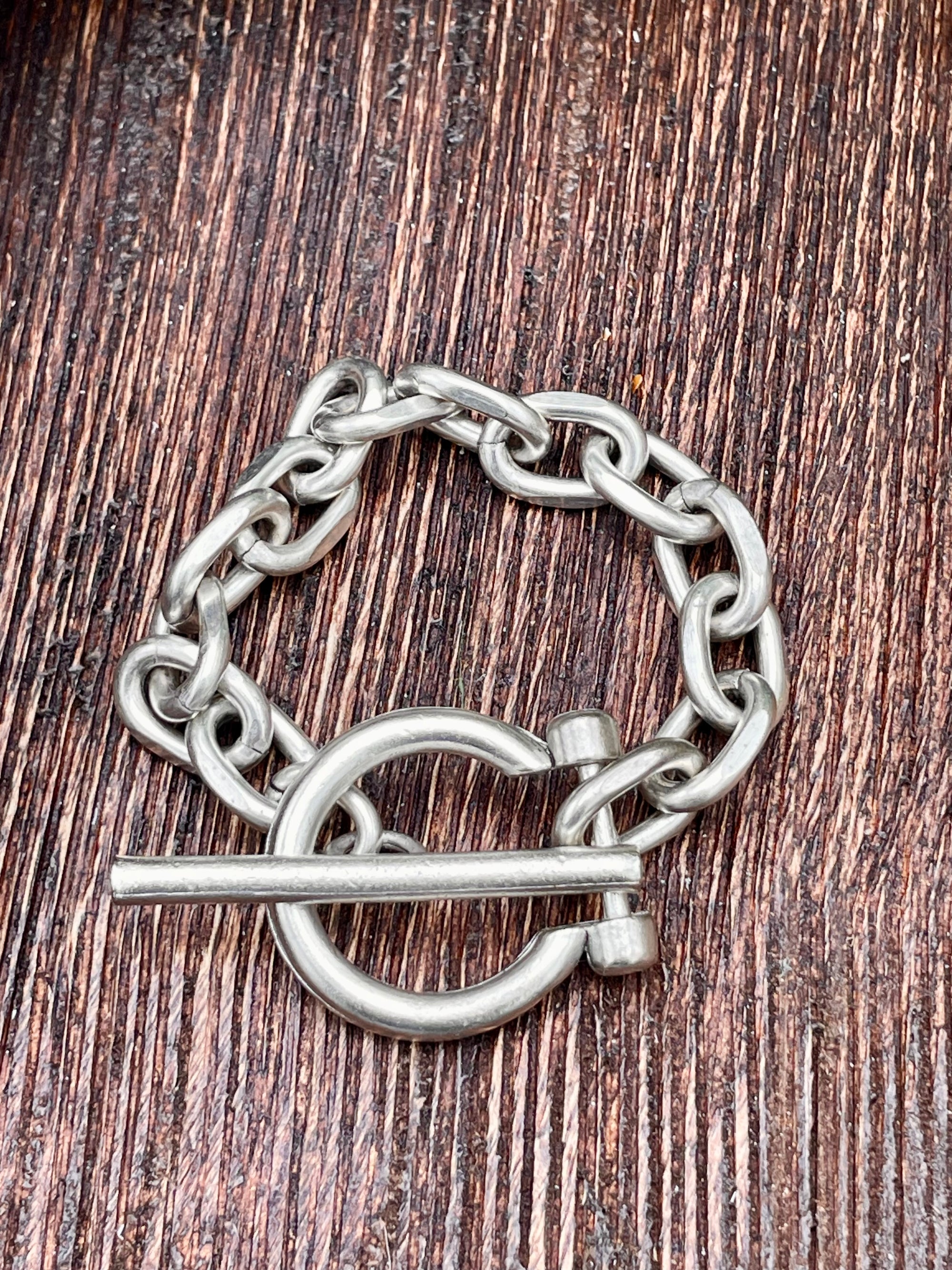 Silver chain bracelet with toggle on a wooden surface