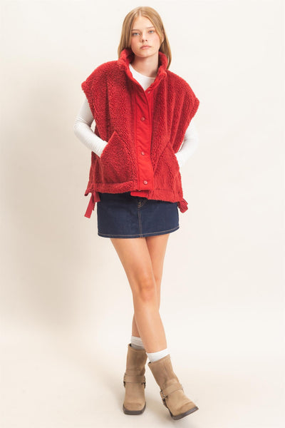 model wearing white shirt and jeans skirt with a red Sherpa Vest over it.